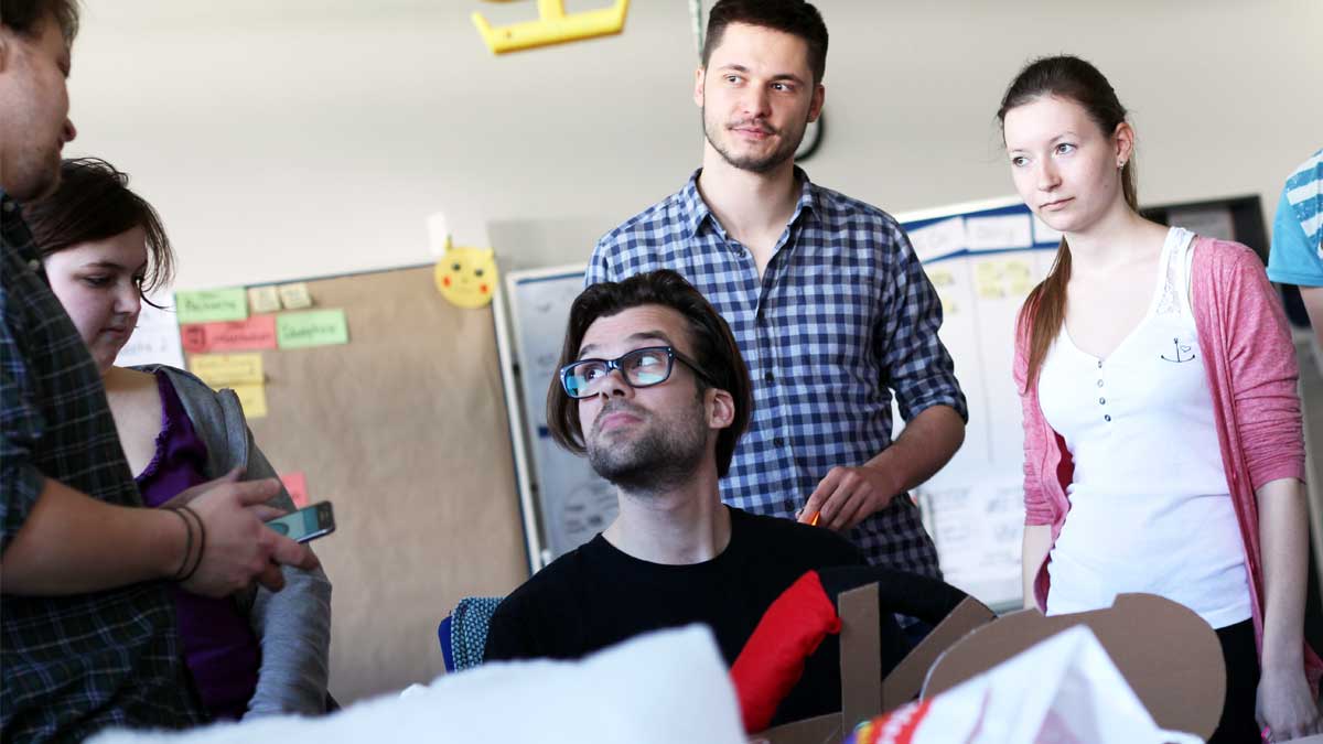 Designer and teacher Hannes Jentsch surrounded by 4 students while testing a physical prototype